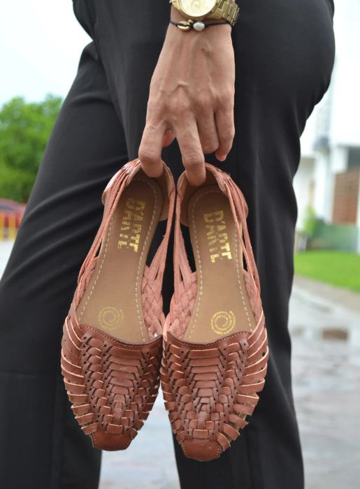 A model is shown holding the brown huarache slip-ons in their hand