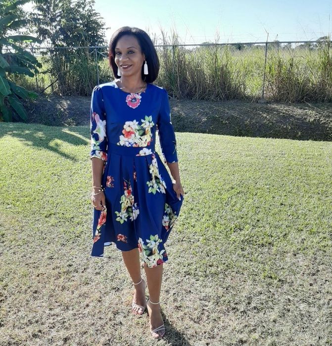 reviewer wearing the blue dress with white floral patterns and strappy heels