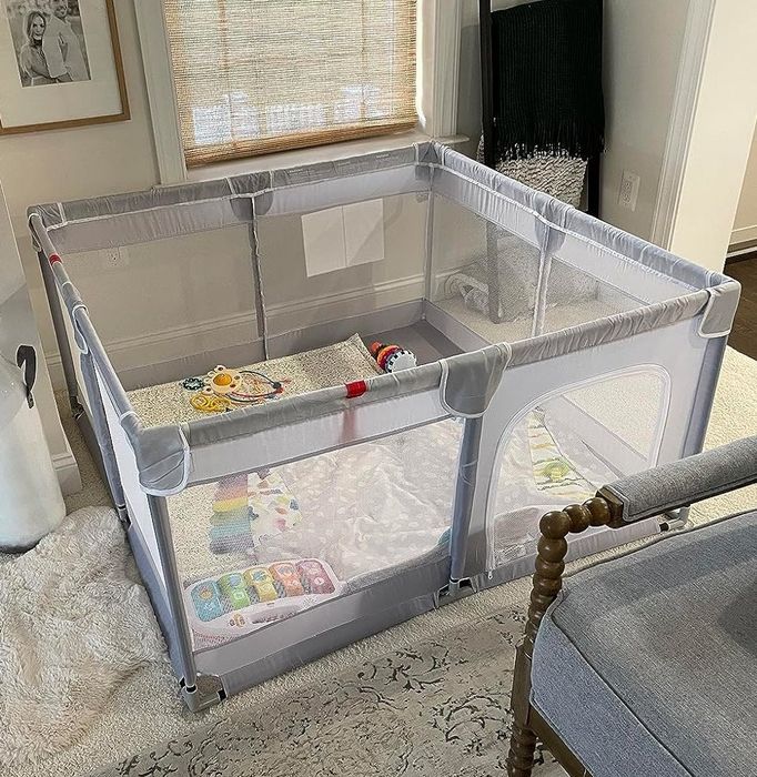A portable playpen filled with toys, set up in a living room, highlighting its child-safe features