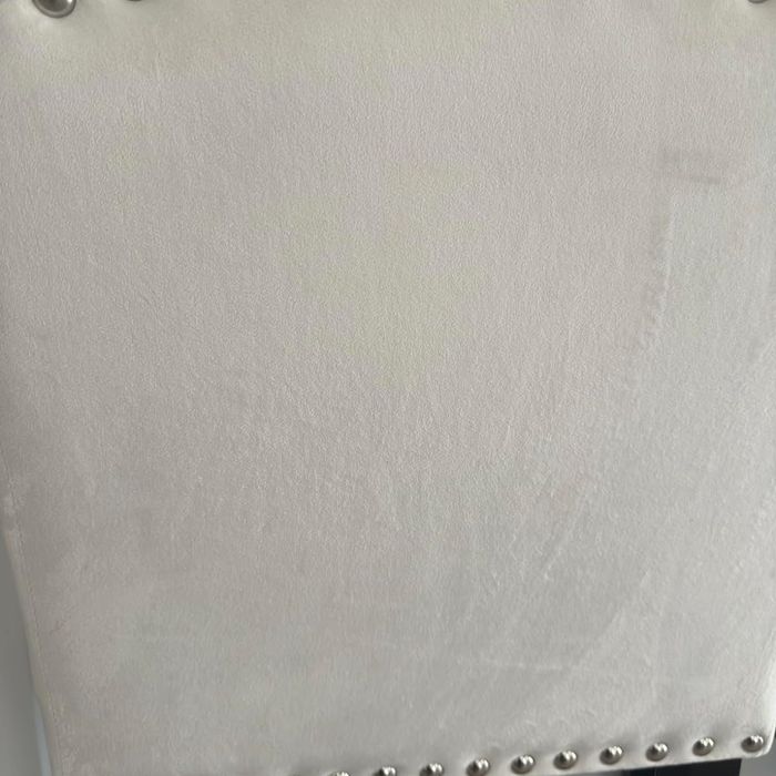 A close-up view of a studded chair with a tufted backrest and wooden legs, perfect for home decor ideas