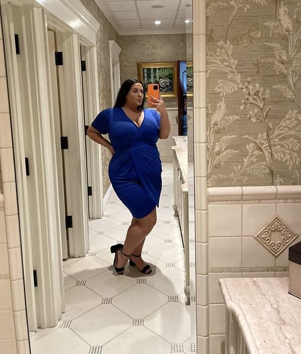 reviewer wearing the blue dress with black heels, posing in front of a mirror