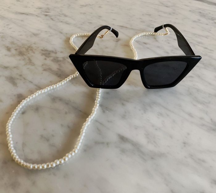 The reviewer has attached the pearl chain to their black sunglasses.