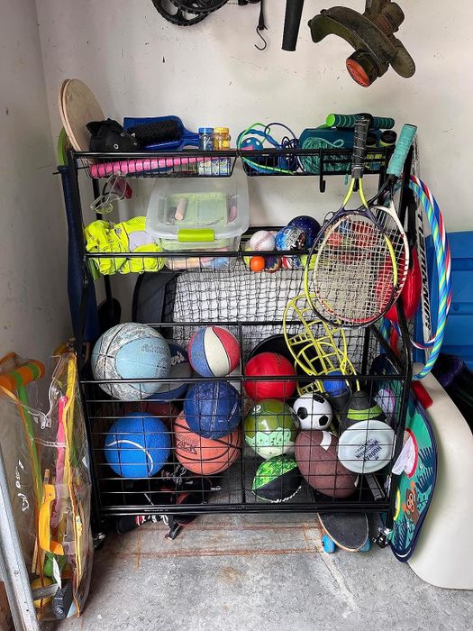 A rack displaying various sports gear, such as basketballs, footballs, tennis rackets, baseball gloves, and other athletic equipment.