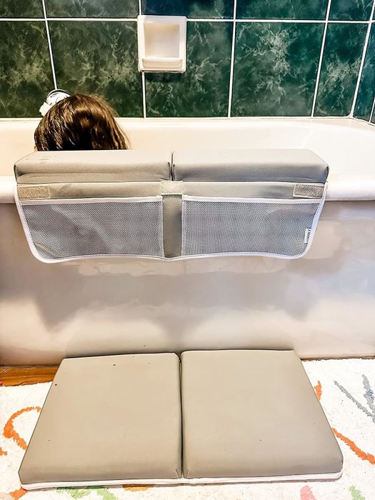 A cushion on the floor alongside an elbow rest, designed to provide comfort and support during bathtime