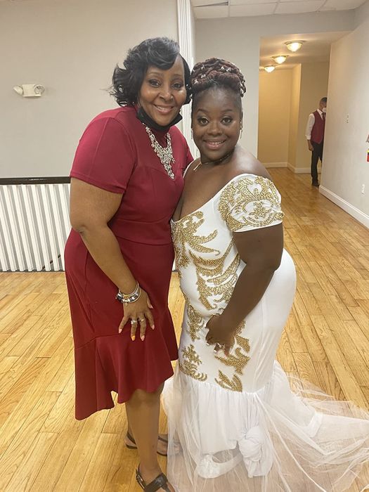reviewer wearing the red dress posing with another person in a white gown adorned with gold designs