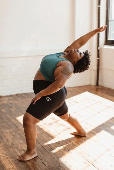 A model is shown wearing black bike shorts while performing a yoga pose