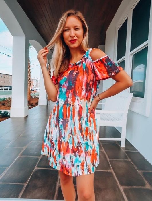 reviewer wearing the dress featuring a white, blue, and red patterned design