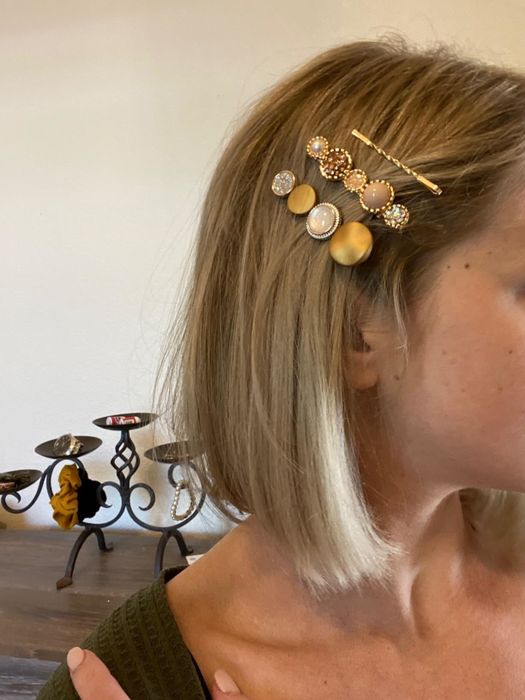 The reviewer is showcasing three different gold barrettes styled in their hair.