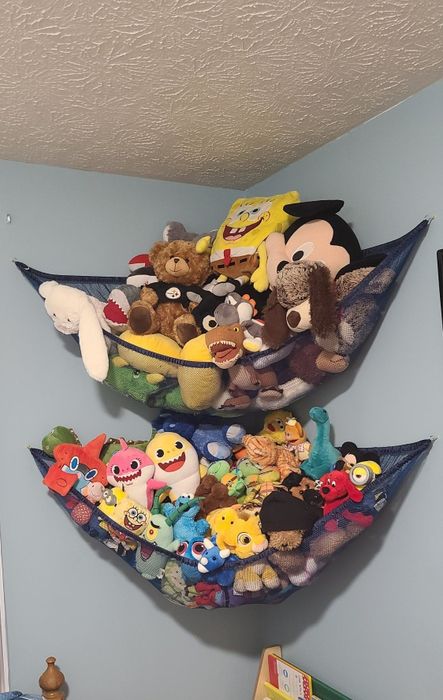 Wall-mounted fabric storage pockets filled with various plush toys, including SpongeBob and Mickey Mouse.