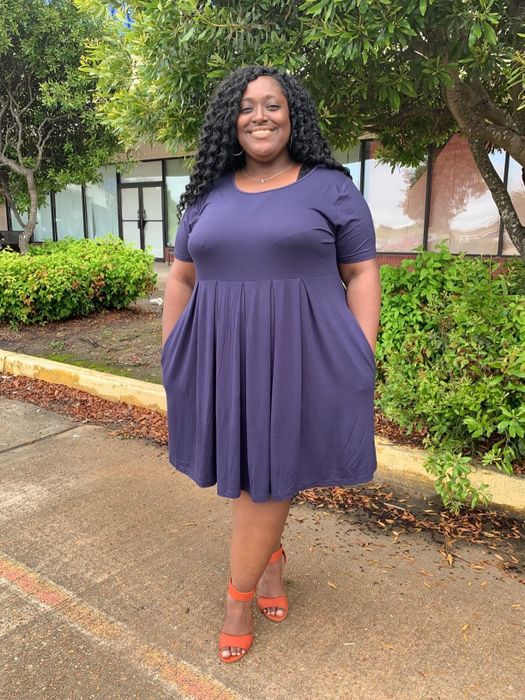 reviewer wearing the purple dress paired with orange heels