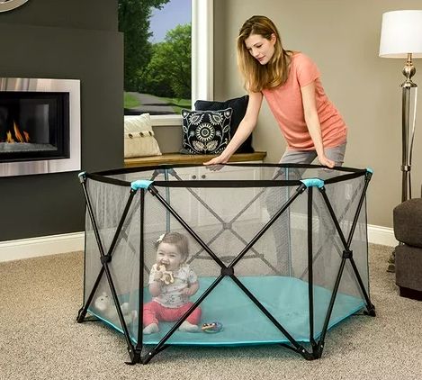 A play yard with a baby inside, set up in a living room
