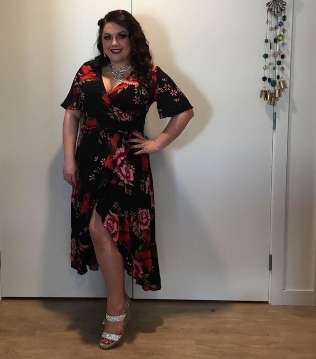 reviewer wearing the black dress with red floral patterns and sparkling wedges