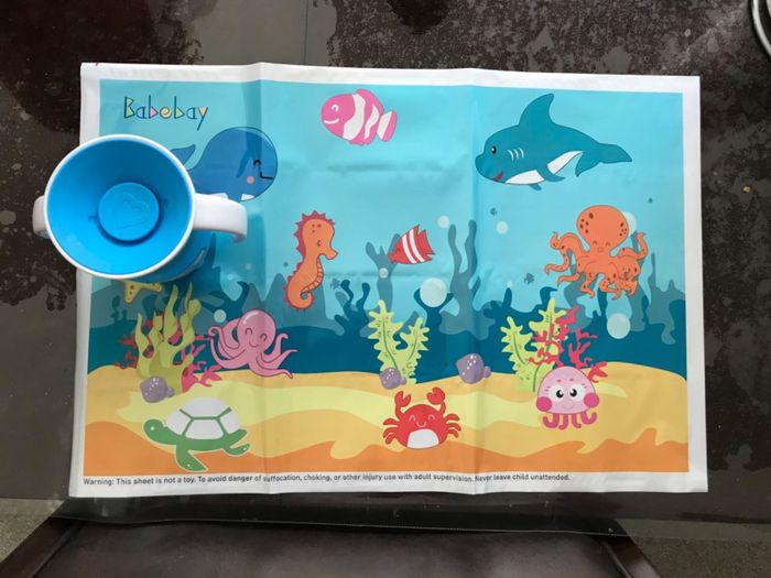 A depiction of sea creatures and a plastic cup on a child’s placemat