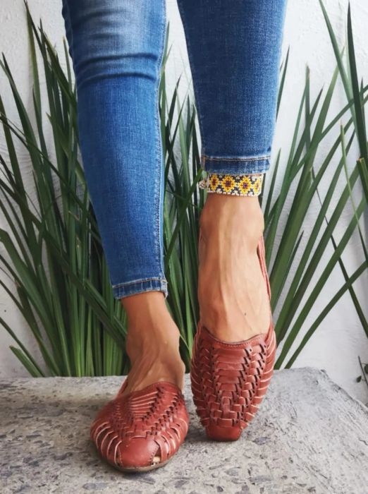 A model is pictured wearing the brown huarache slip-ons with jeans
