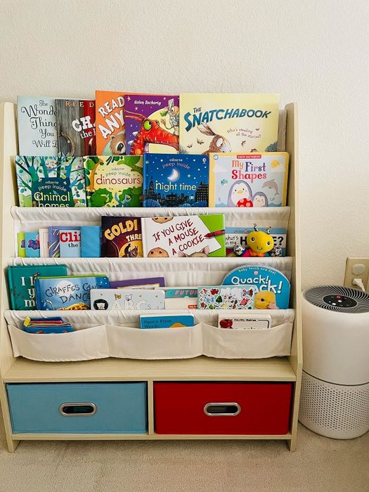 A bookshelf filled with a variety of children's books, accompanied by a play area that features storage bins for added organization.