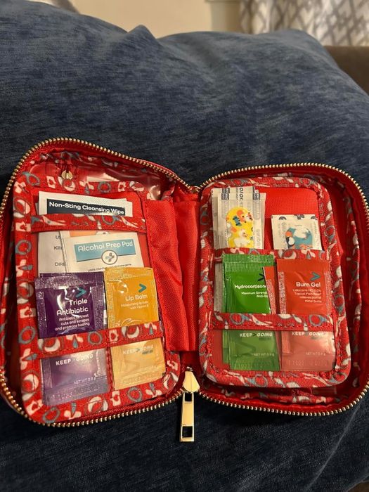 A first aid kit stocked with various supplies, including bandages, alcohol prep pads, triple antibiotic ointment, lip balm, hydrocolloid bandages, and burn gel