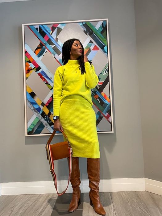 A reviewer is seen sporting the bright yellow ribbed pencil skirt and matching crewneck sweater.