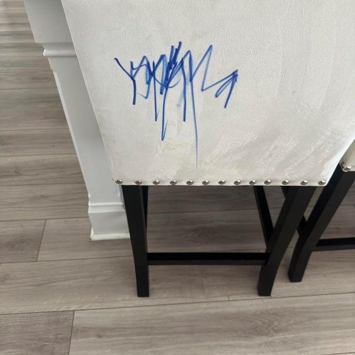 A white chair featuring studded accents and a blue signature on the backrest