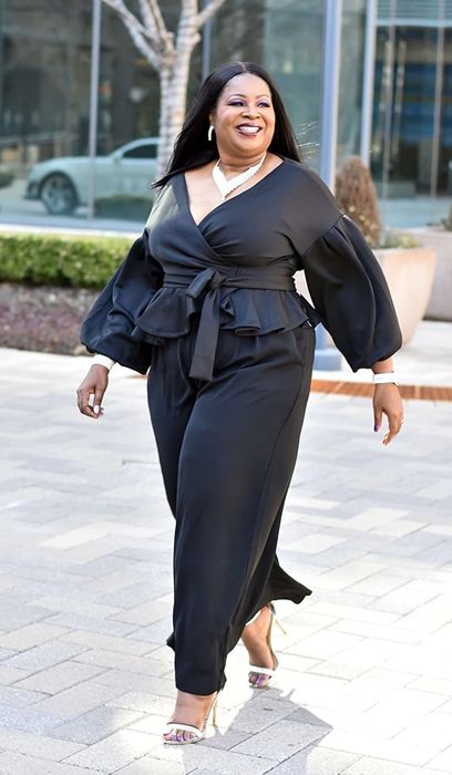 The reviewer is showcasing the blouse in a sleek black color.
