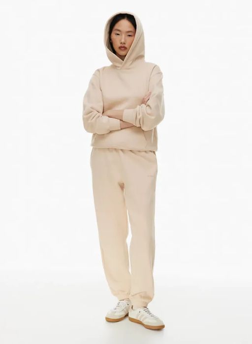A person in a casual hoodie and sweatpants outfit, standing with arms crossed