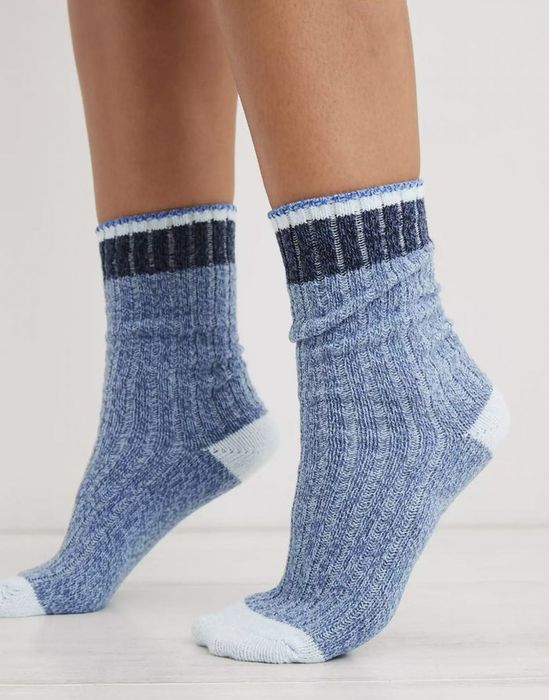 An individual balancing on tiptoe wearing blue colorblock crew socks