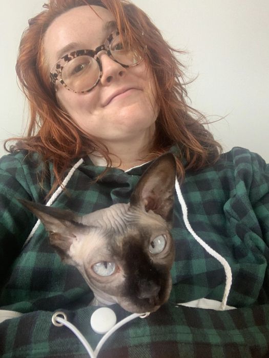 A Mytour writer wearing the sweatshirt with a hairless cat comfortably sitting inside the pouch