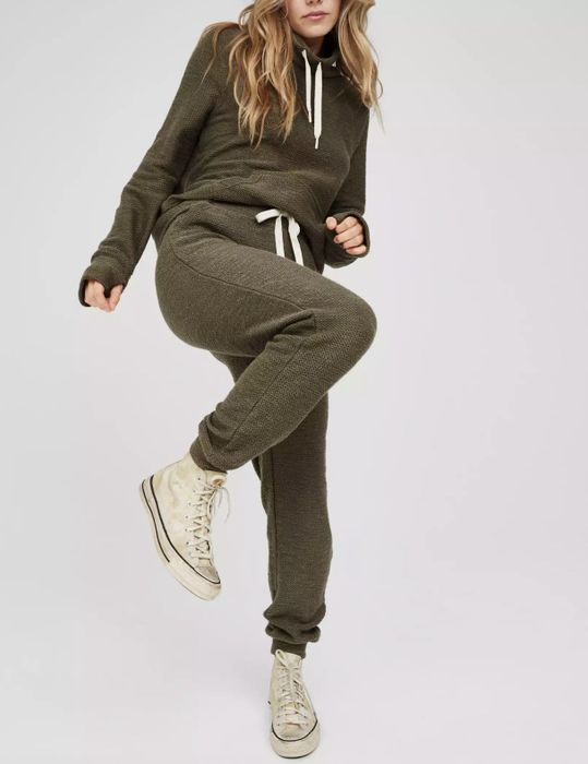 The model is raising her knee while wearing the green joggers.