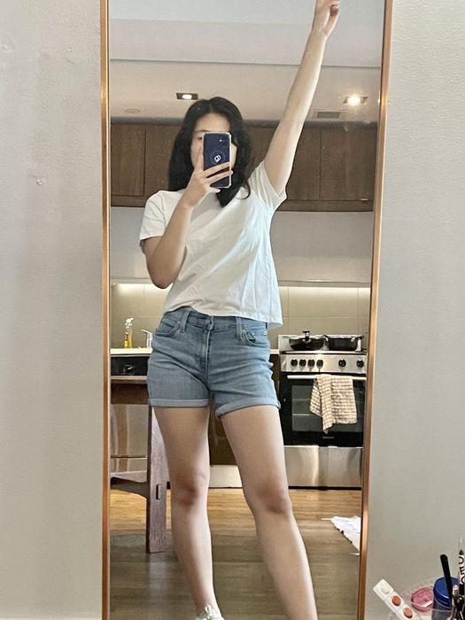 A writer sporting shorts while standing in front of a full-length mirror.