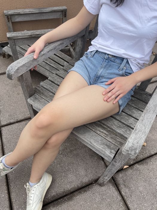 A writer wearing shorts, sitting on a chair outdoors.
