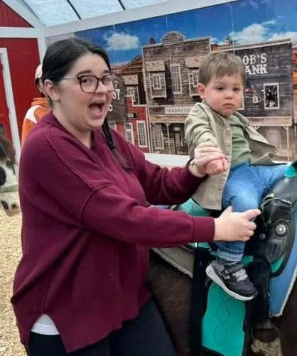 a Mytour editor and a toddler riding a horse; the editor is excited while the child remains calm