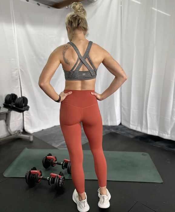 another reviewer wearing the orange leggings at the gym for a workout