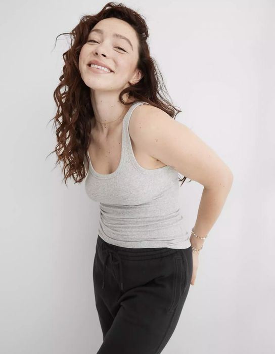 The model is wearing a grey tank paired with black sweatpants.