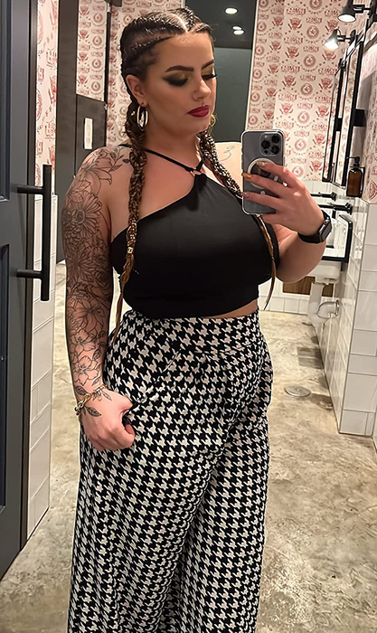 A reviewer is pictured wearing the houndstooth-patterned pants.