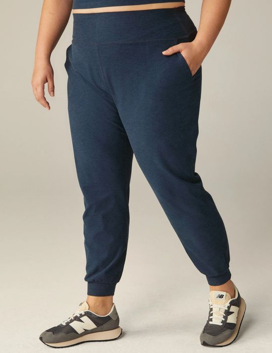 A person is standing, wearing navy blue joggers and multicolored sneakers, with the focus on the lower half of the body.