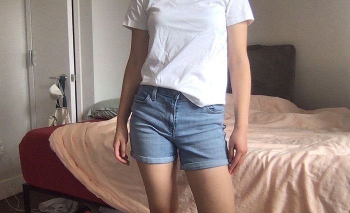 A writer wearing shorts, standing in a bedroom.