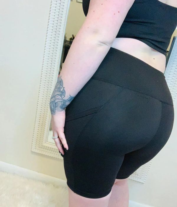 A person dressed in black shorts and a top, demonstrating the fit; ideal for an article about shopping for athletic wear