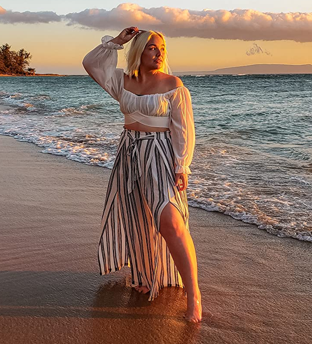 Side view of a reviewer wearing black and white striped pants on the beach.