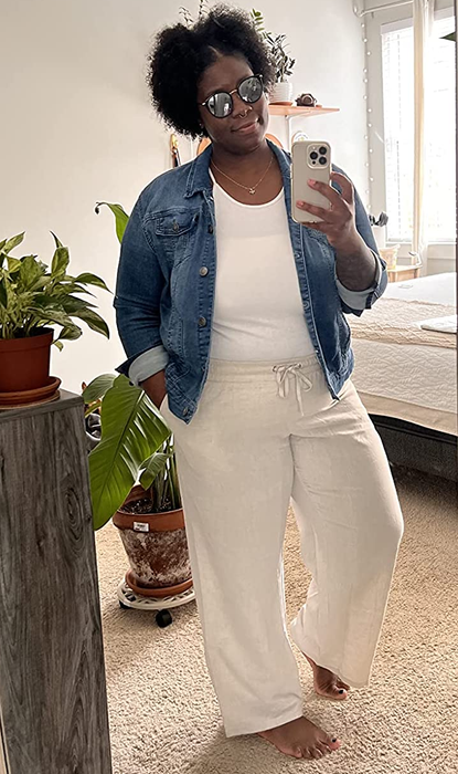 A reviewer is pictured wearing the beige pants paired with a denim jacket.