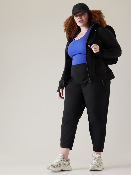 A model is shown in casual sportswear, wearing a jacket, cropped pants, and sneakers.