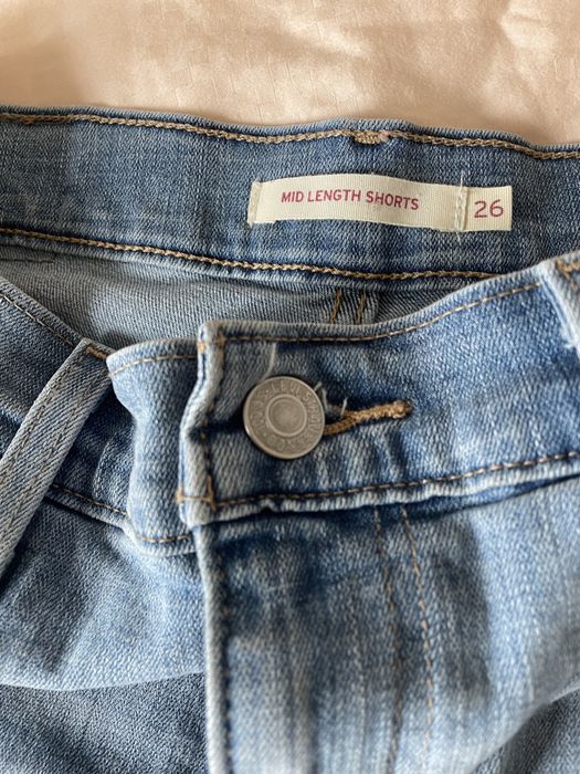 A close-up shot of the seams and the tag on the back of the shorts. It reads 'Mid Length Shorts 26'.