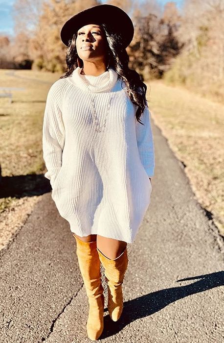 Reviewer wearing the white turtleneck dress with knee-high boots.