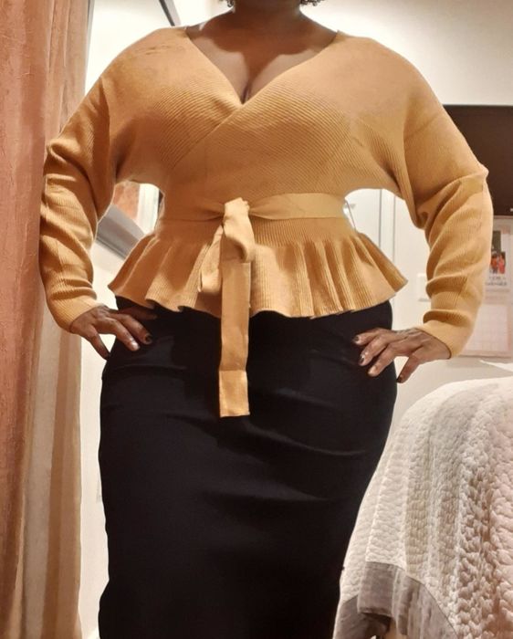 A close-up shot from a reviewer shows the camel-colored sweater paired with a long black skirt.