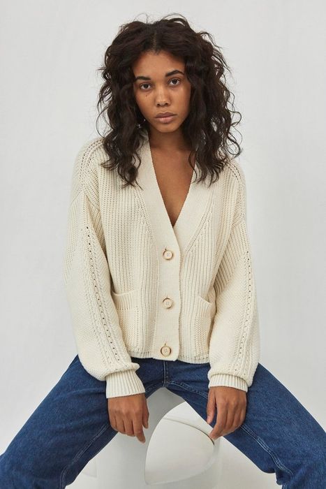 Model showcasing the white sweater with pockets.