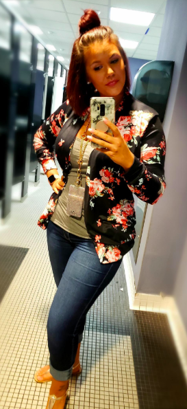 A reviewer styling the hip-length black and pink floral cardigan