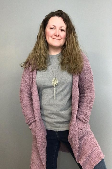 The reviewer is wearing a long pink cardigan.