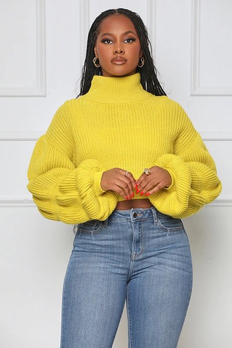 The model is wearing a cropped yellow cable knit sweater.