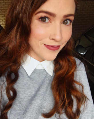 A reviewer is seen wearing a gray sweater featuring a crisp white collar.