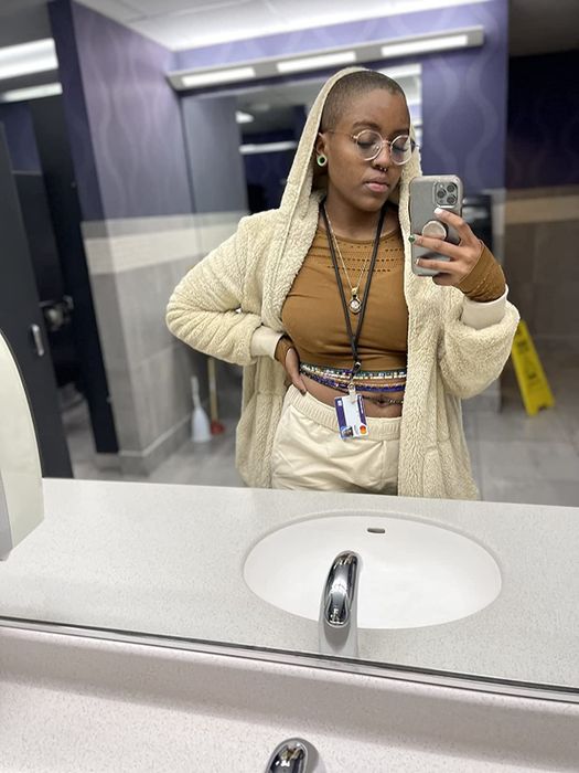 Reviewer wearing a beige fuzzy cardigan over a brown shirt and beige pants