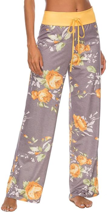 A model wearing wide-leg gray and yellow floral pants featuring a yellow drawstring waistband