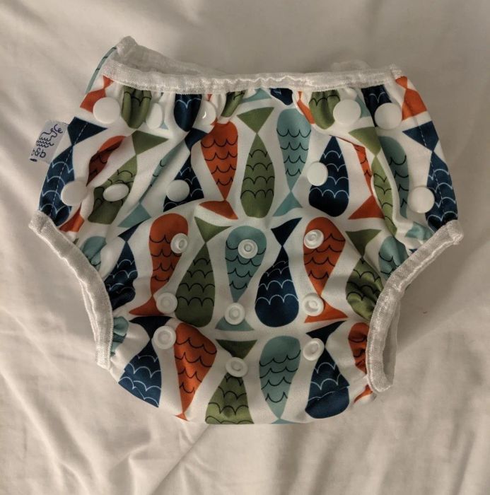 Reviewer's photo of the reusable swim diaper showcasing a colorful fish print, displayed flat on a white background